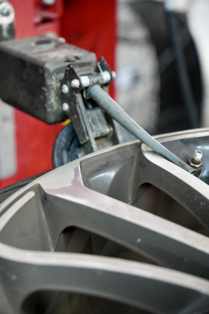 A close-up of a metal machine tool working on the edge of a car wheel rim, showcasing the manufacturing or repair process that helps extend tire life and optimize tire performance.
