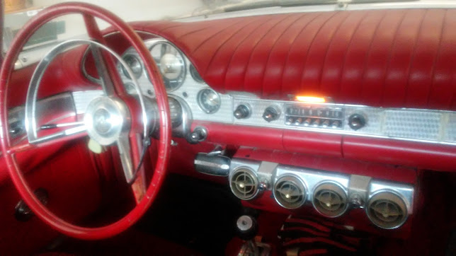 Interior of a classic car with a red dashboard, silver instrument panel, round gauges, red steering wheel, and four circular air vents below—perfect for Florida drivers who appreciate both style and the importance of regular oil changes.